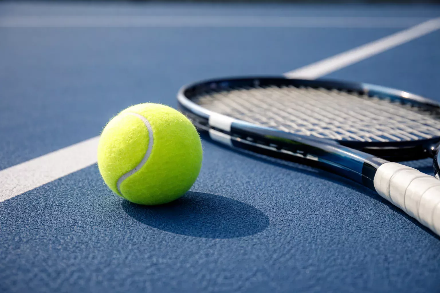 Pallina da tennis e racchetta su campo in cemento